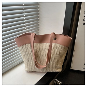 Detail view of woven tote bag featuring pink faux leather handles and creamy straw texture