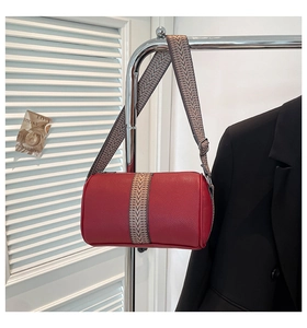 Detail der roten Zylindertasche aus Leder mit gewebtem Gurt an einem Metallhänger