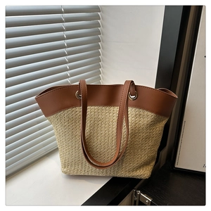 Close-up of woven straw tote bag featuring brown leather handles and metal hardware