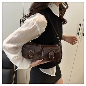 Détail du sac baguette vintage marron avec deux poches à boucles et rivets argentés