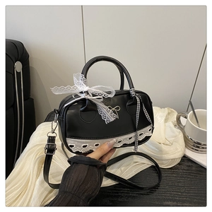 Détail du sac bowling en cuir noir avec nœud en dentelle blanche et bandoulière réglable