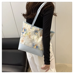 Close-up of floral jacquard texture and light blue stitching on a large tote bag