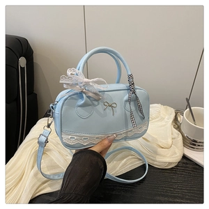 Détail du sac bowling bleu clair avec bordure en dentelle blanche et nœud argenté