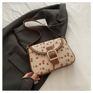 Détail du sac cabas en toile à imprimé cerise avec garniture cuir et boucle dorée chic