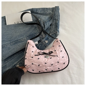 Détail du sac à bandoulière rose plissé avec nœud en ruban noir et pendentif cœur argenté