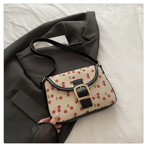 Détail du sac bandoulière en toile beige avec imprimé cerise et boucle en métal doré