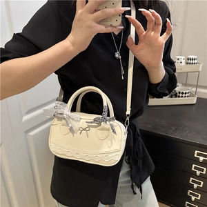 Petit sac bowling blanc crème avec nœud et dentelle porté par un mannequin femme