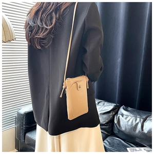 Back view of a woman wearing the apricot faux leather crossbody phone bag on the shoulder