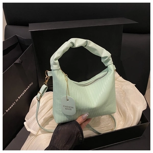 Detail of mint green pleated handbag with ruffle handle on white satin in a black box