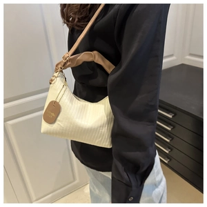 Close-up of beige pleated bucket bag with brown leather strap and fashion tag detail