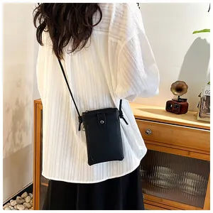 Detail of a black lychee-textured leather crossbody phone bag with an adjustable strap