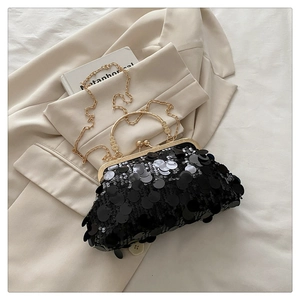 Macro shot of black sequins evening bag with gold clasp and chain on beige jacket