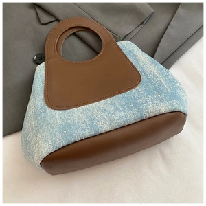Close-up of vintage blue denim handbag with rhinestones and brown leather handles