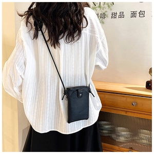 Detail of the black textured leather phone crossbody bag with slim strap and metal zipper
