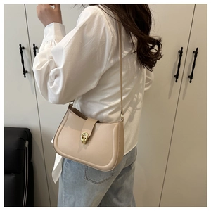 Detail view of the beige leather shoulder bag with gold clasp shown on a model
