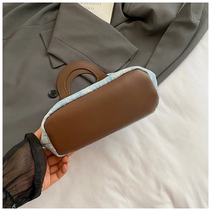 Detailed view of blue denim and brown leather patchwork on this casual bucket tote bag