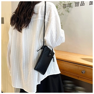 Rear view of model wearing a black vertical leather crossbody phone bag with texture