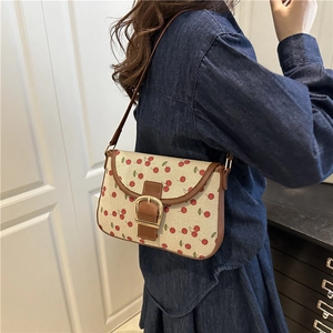Sac bandoulière en toile imprimé cerises avec bordure en cuir marron sur un mannequin
