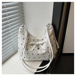 Détail du sac à bandoulière blanc matelassé avec nœud et pendentif cœur en argent