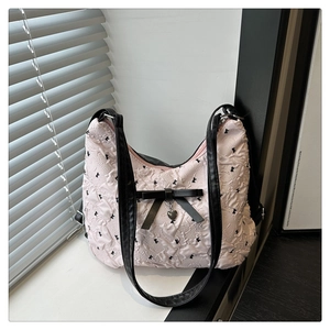 Détail du sac plissé rose avec motifs de nœuds noirs et breloque en forme de cœur
