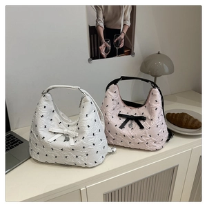 Détail de sacs hobo matelassés avec broderie mini nœuds noirs et pendentif cœur