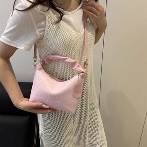 Sac hobo plissé rose avec bandoulière réglable porté par un mannequin chic