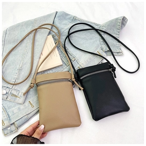Vertical crossbody phone bag detail in khaki and black leather on denim jacket