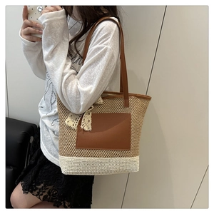 Detail of woven straw tote bag with brown leather trim and white lace bow accessory