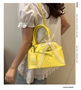 Close-up of vibrant yellow shell bag with white lace bow and chic logo hangtag detail