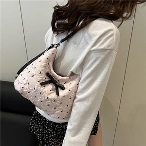 Sac fourre-tout matelassé rose avec nœuds noirs et breloque cœur porté par un mannequin