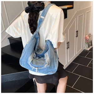 Dettaglio della borsa tote in denim blu con bordi sfrangiati e tracolla larga regolabile