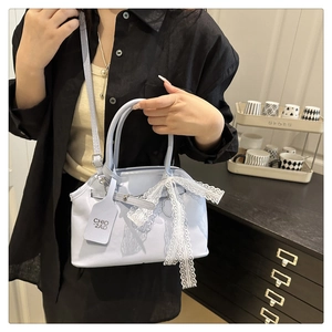 Detail showing a light blue leather bag with a white lace bow and adjustable strap