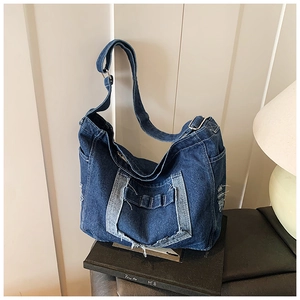 Dettaglio della borsa hobo in denim blu con bordi vintage sfrangiati e tasca frontale