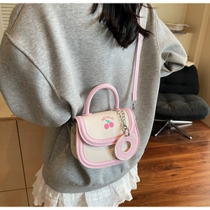 Detail of cute cherry print saddle bag with a sweet donut charm in a crossbody view
