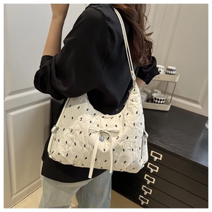Detail of white pleated crescent bag featuring black rabbit prints and a bow charm