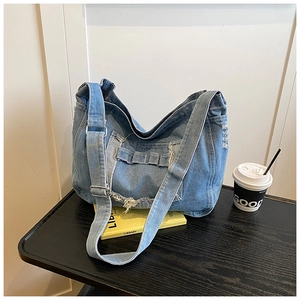 Dettaglio ravvicinato della borsa in denim lavato con toppe floreali retrò consumate