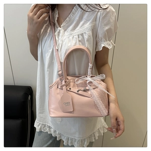 Pink leather handbag with lace bow detail and brand tag shown on model in modern room