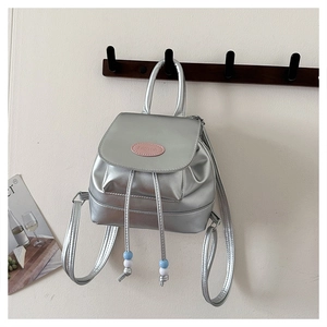 Detail eines silbernen Metallic-Rucksacks mit Kordelzug und Markenlogo aus PU-Leder