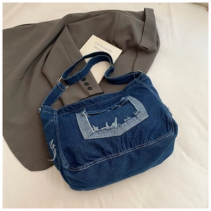 Dettaglio ravvicinato della borsa a tracolla in denim blu scuro con tasca a fiori sfrangiata
