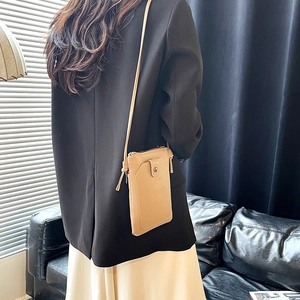 Minimalist beige pebble leather crossbody phone bag with thin strap on a professional model