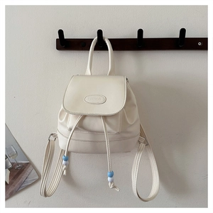 Detail eines cremefarbenen Vintage-Lederrucksacks mit Kordelzug und blauen Perlenakzenten