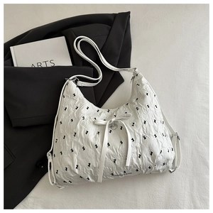 Detail of white hobo bag with black bow patterns and elegant pleated texture finish