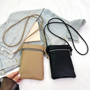 Minimalist leather crossbody phone bag in black and khaki with silver zippers on denim