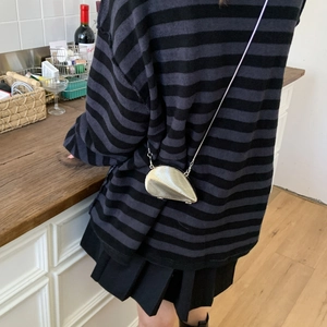 Mini shell-shaped metallic crossbody bag with chain strap shown in a modern lifestyle setting