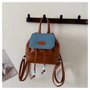 Detail eines Vintage-Patchwork-Rucksacks mit braunem Kunstleder und blauem Denim-Deckel