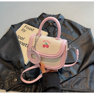 Détail du sac selle rose et crème avec imprimé cerise et breloque donut mignonne