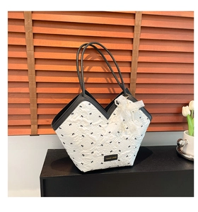 Close-up of V-shaped white tote bag with black bow prints and lace pearl charm