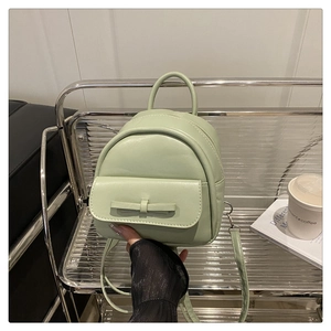Detail of mint green mini backpack with bow decoration and smooth synthetic leather texture