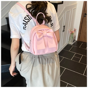Close-up of a pink mini backpack with a large decorative bow and adjustable PU leather straps