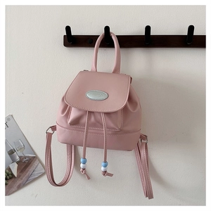 Detailansicht eines rosa Mini-Rucksacks mit Kordelzug und metallenem Markenlogo-Schild
